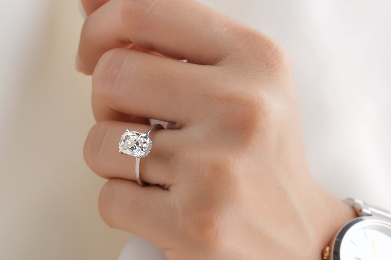 close up image of a woman’s hand wearing a silver solitaire engagement ring
