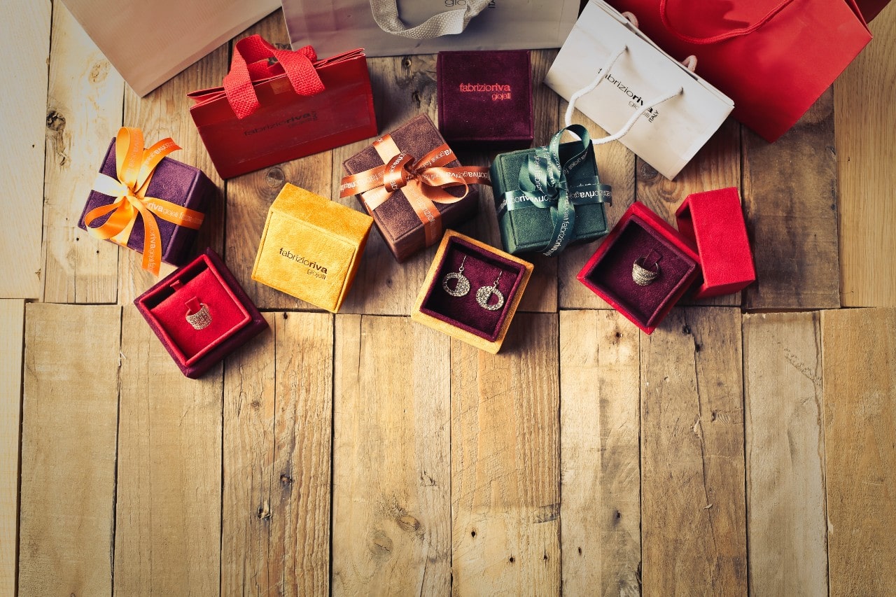 A variety of colourful gift boxes and jewelry pieces arranged on a wooden surface, showcasing luxury packaging and sparkling accessories.