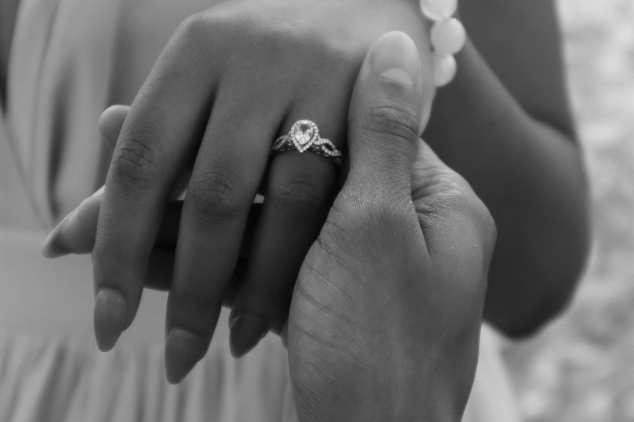 A groom holding his bride’s hand, who is wearing a pear shaped diamond engagement ring