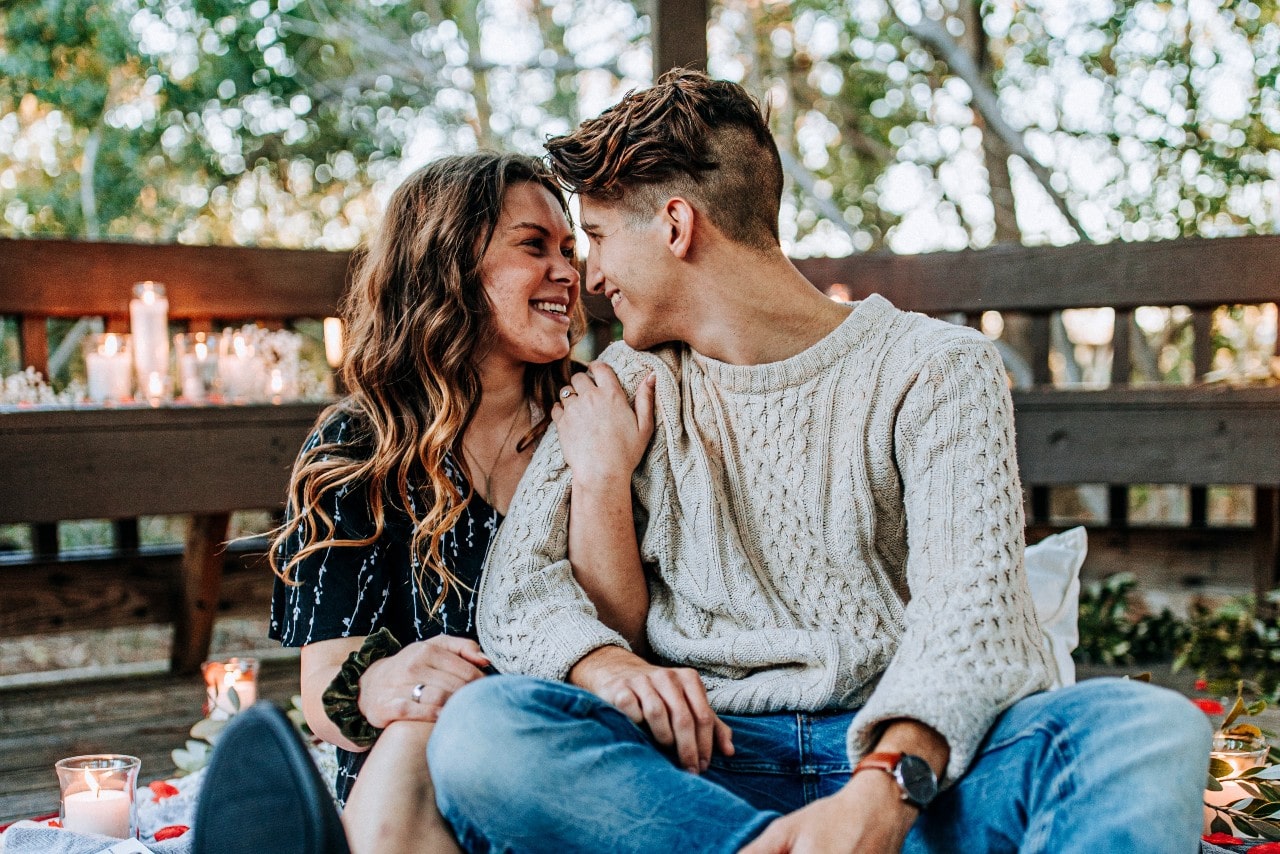 A couple cuddles together in a gazebo with candles in the fall.