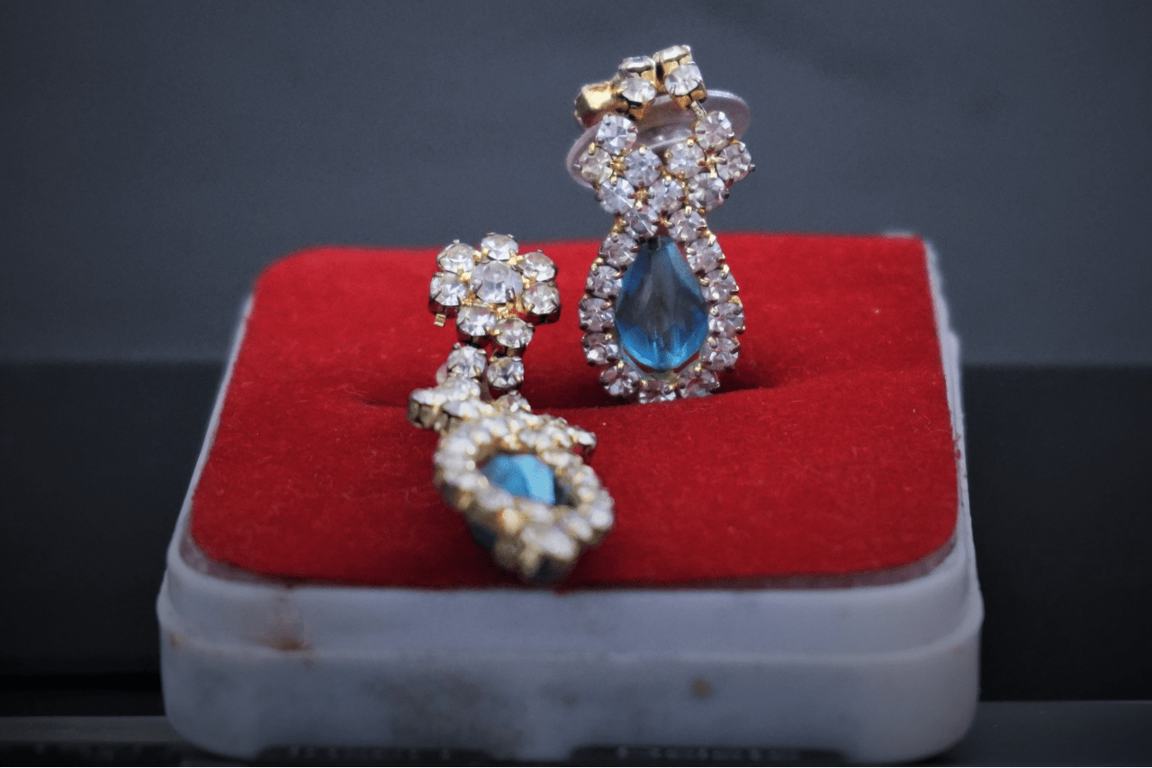 A yellow gold vintage drop aquamarine and diamond earrings inside the red velvet jewelry box.