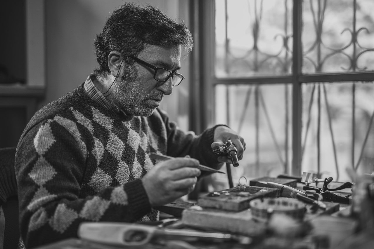 A jeweler solders an engagement ring back together after resizing it in his messy workshop