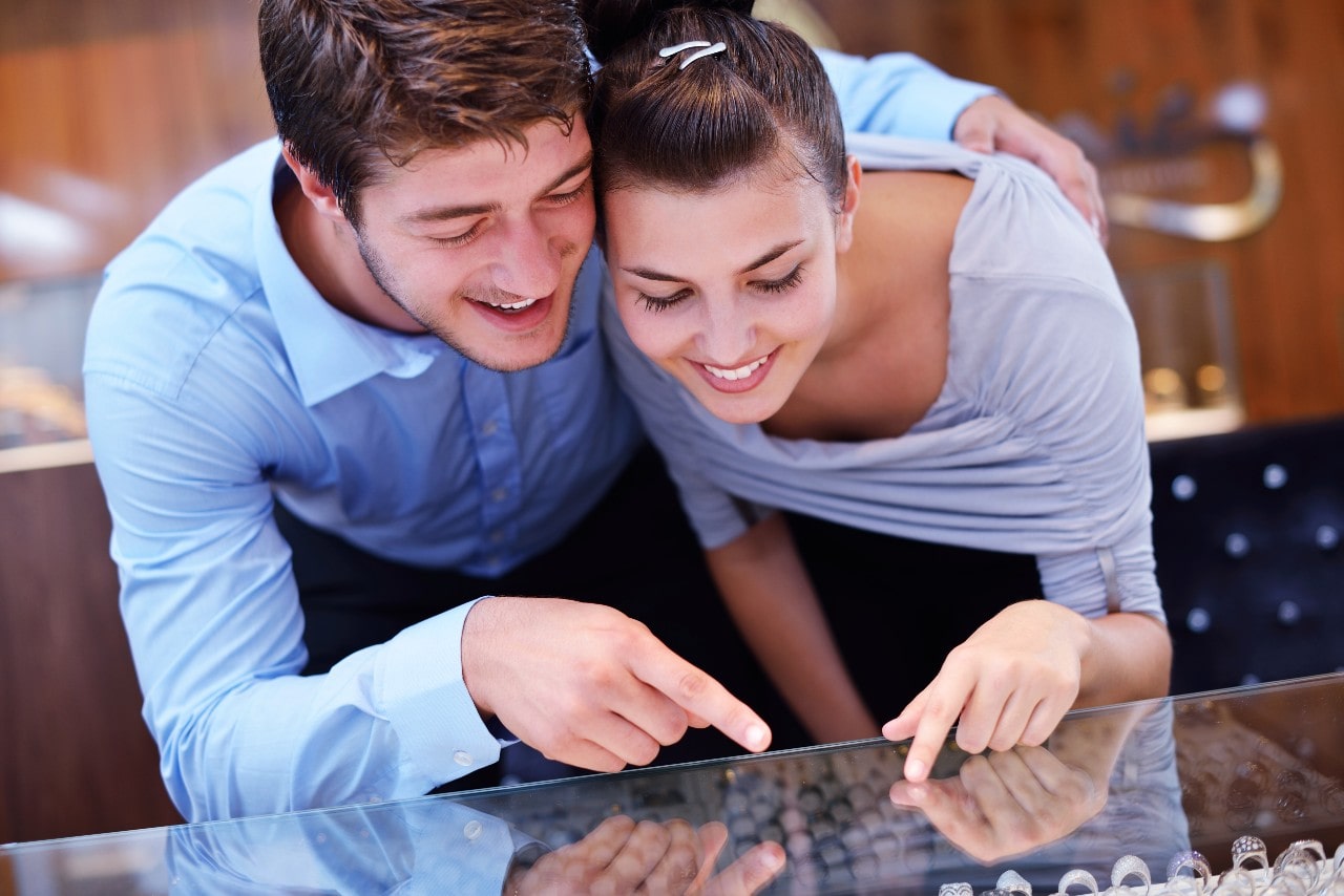 A couple with matching outfits visits a local jewelry store together to shop diamond engagement rings