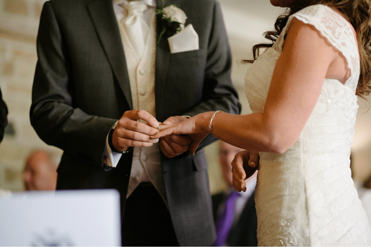 a groom putting a wedding band on a bride’s finger