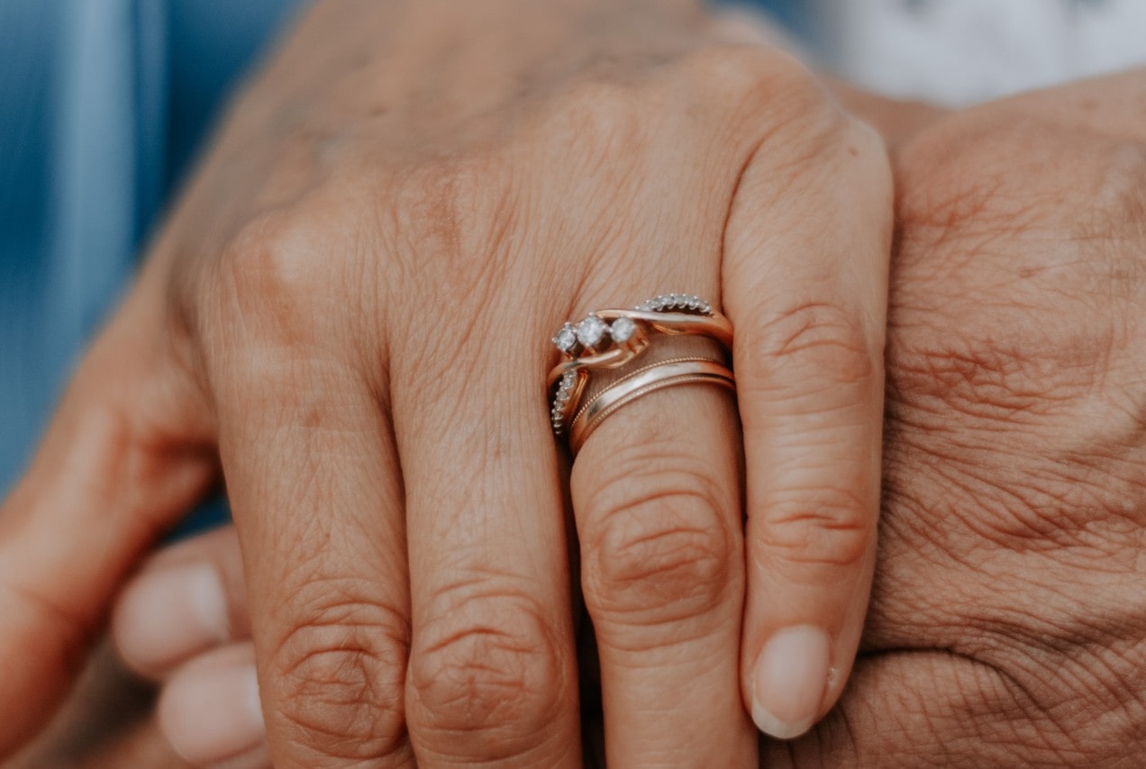 lady’s hand wearing an engagement ring on top of a wedding band