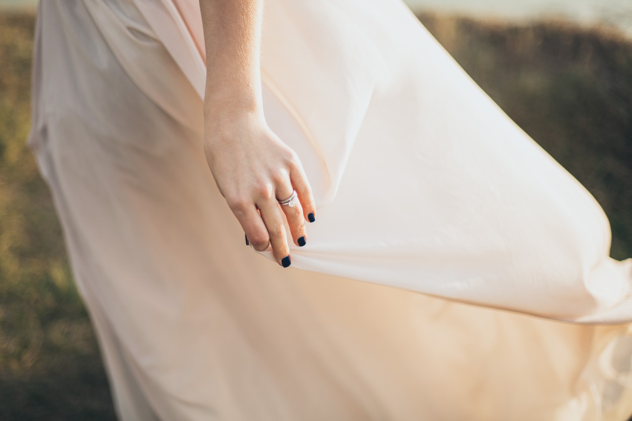 lady’s hand wearing a wedding band on top of an engagement ring