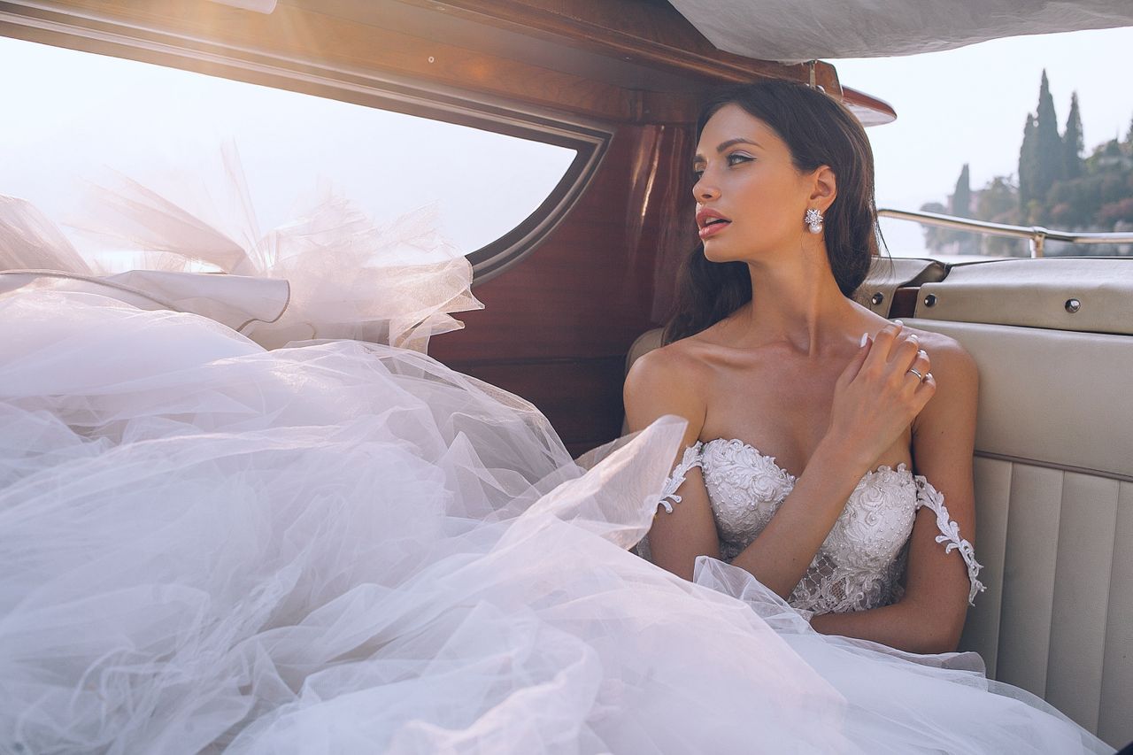lady sitting in a car and wearing a wedding dress and band