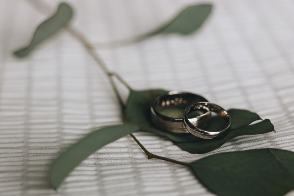 a man and woman’s wedding band resting side by side on a leaf