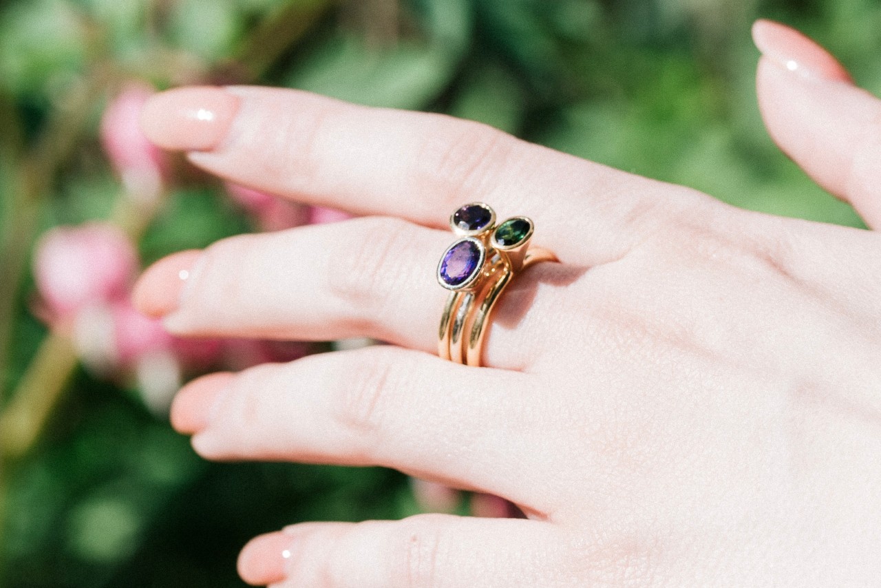 an outstretched hand adorned with three stacked gemstone rings