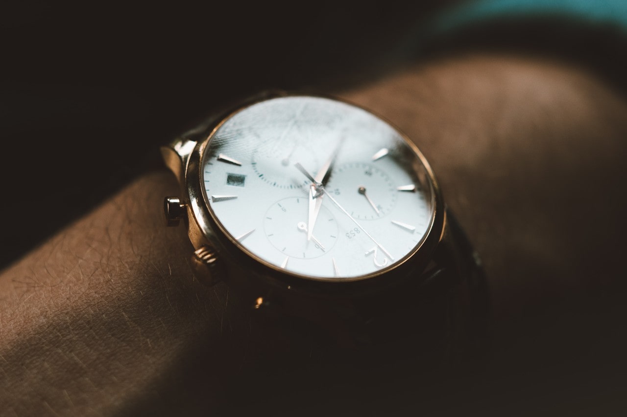 Close up image of a gold watch with a white dial, containing three subdials