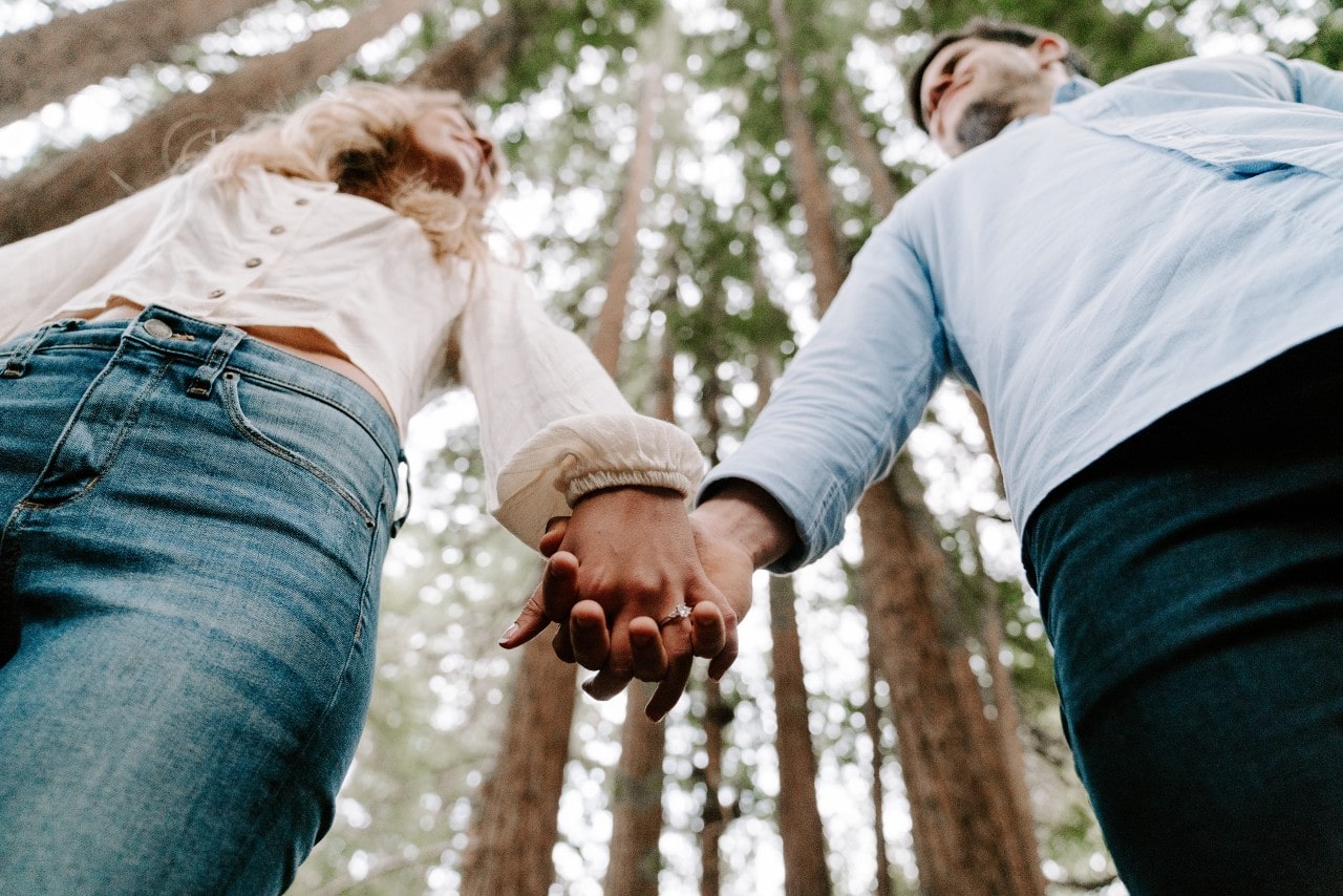 A couple holding hands, showing off the bride-to-be’s Fana diamond engagement ring.