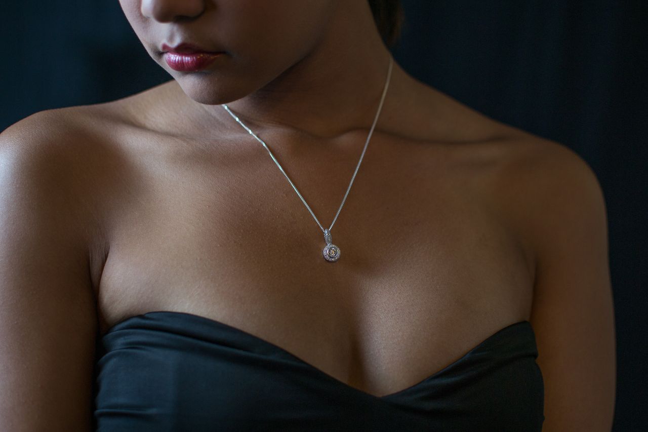 A woman in a black formal dress wears a solitaire diamond necklace. A woman in a black formal dress wears a solitaire diamond necklace.