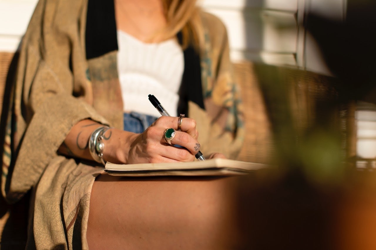 woman with fashion jewelry writing in book