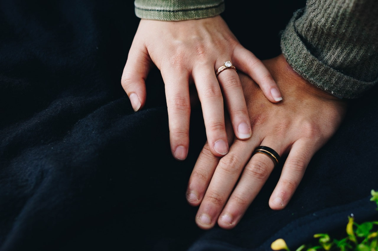 man and woman’s hand wearing wedding rings