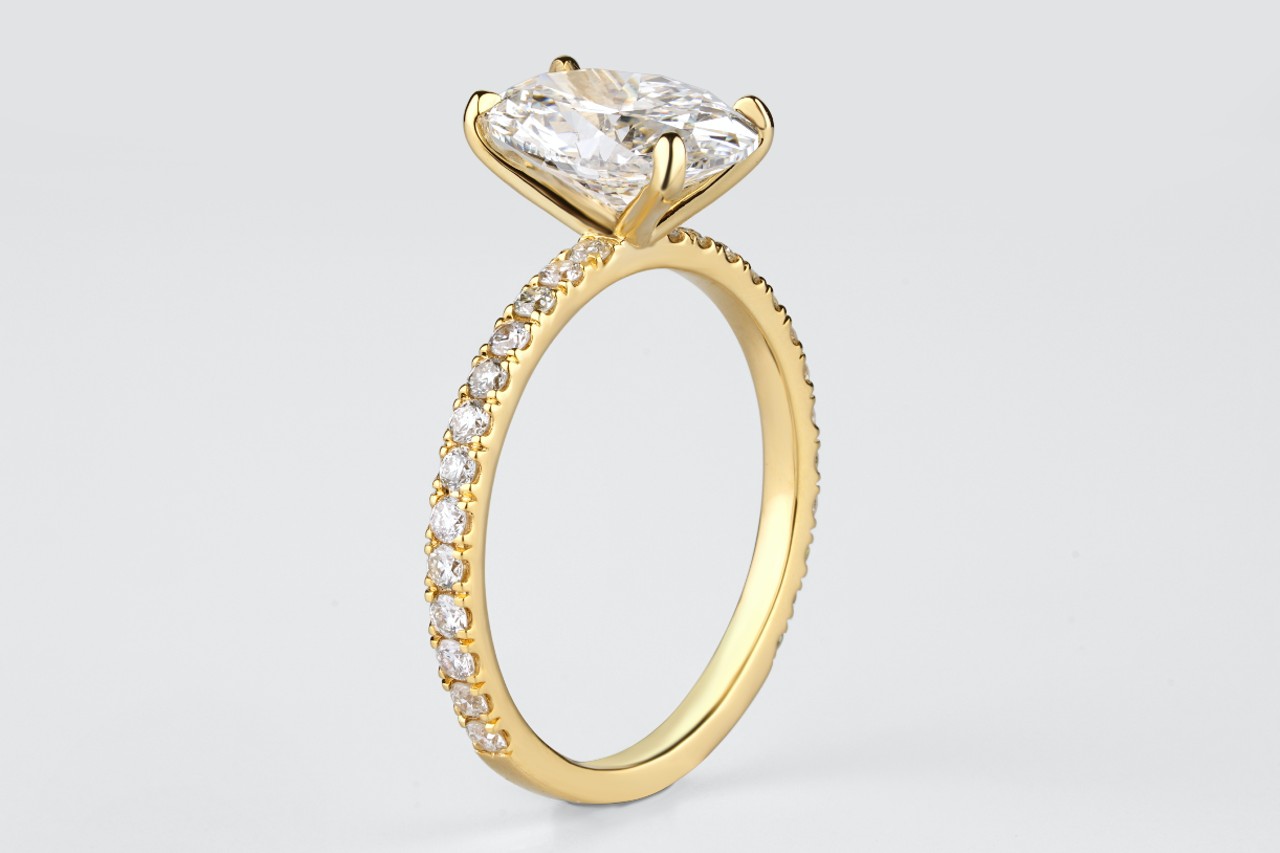 A yellow gold four prong side stone diamond engagement ring.