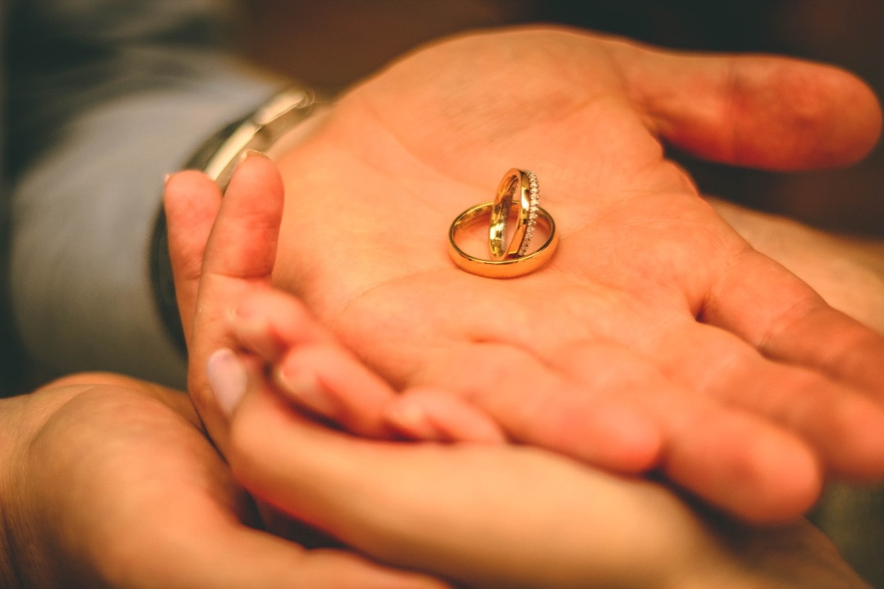 A two yellow gold wedding bands inside the man’s palm