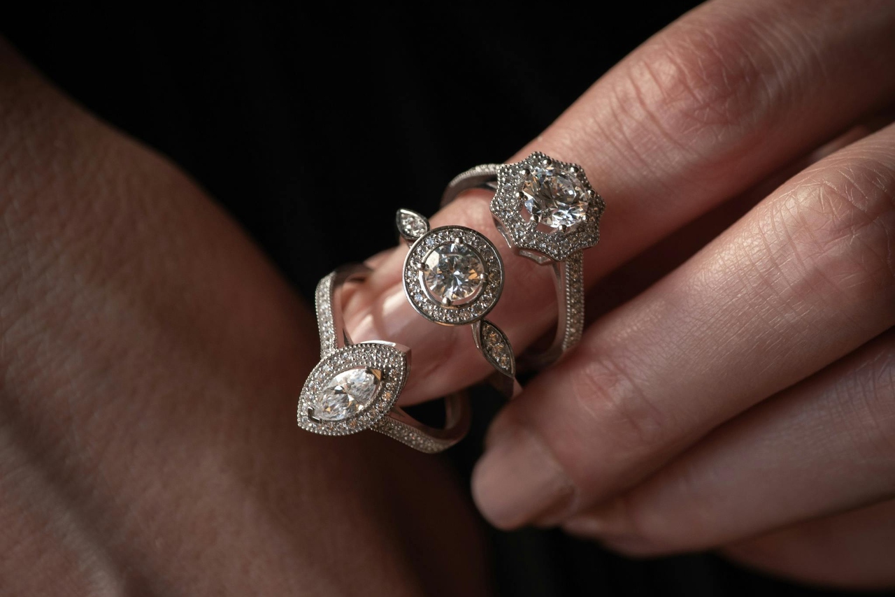 Three white gold diamond engagement rings placed on one finger.