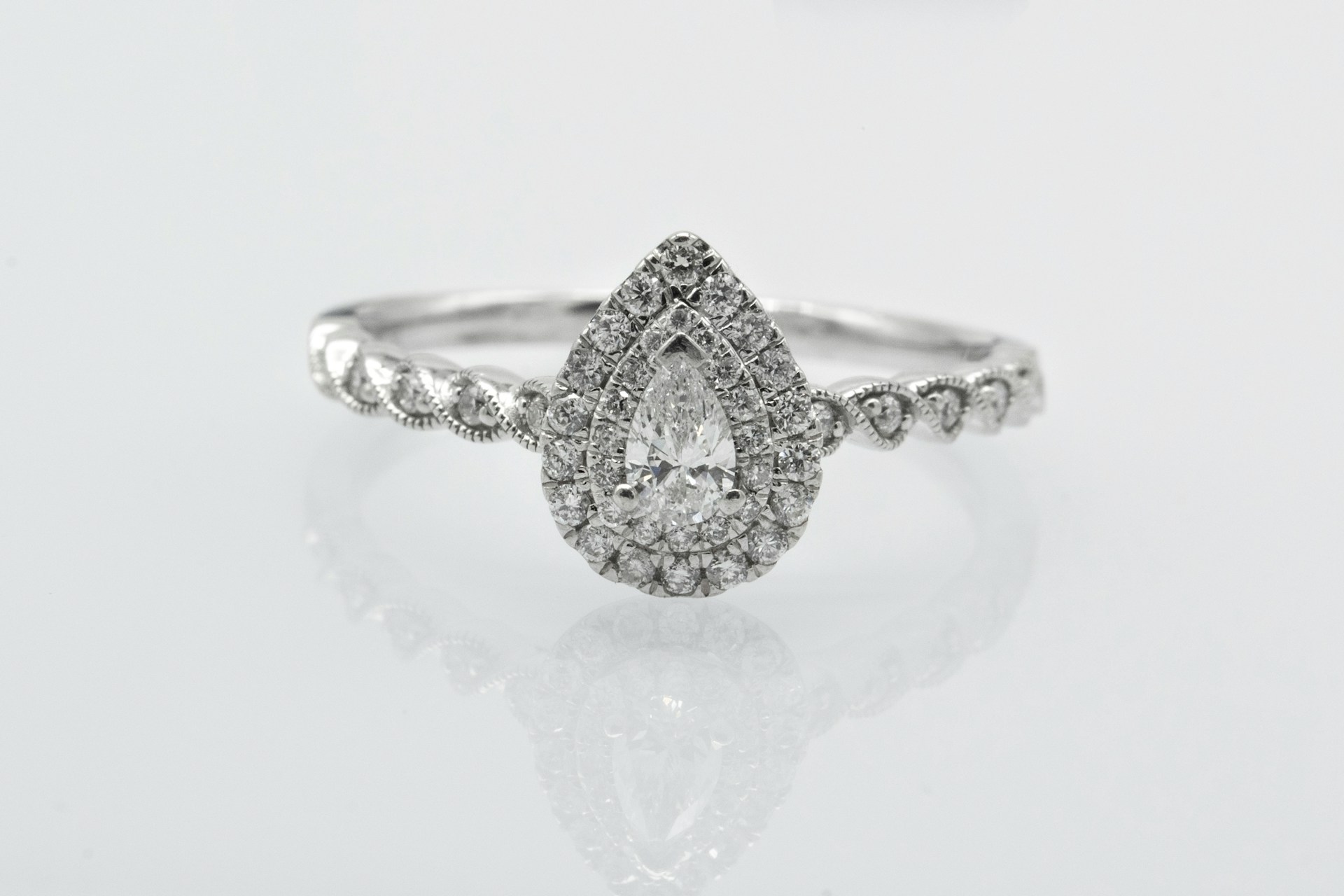 a pear shape engagement ring featuring a double halo and side stones