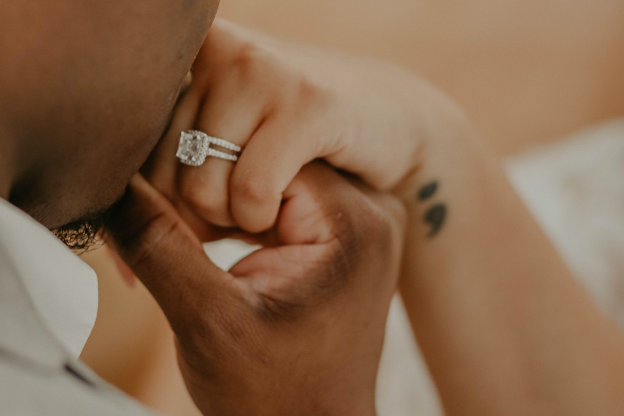 a man kissing a woman’s hand who is wearing an emerald cut engagement ring