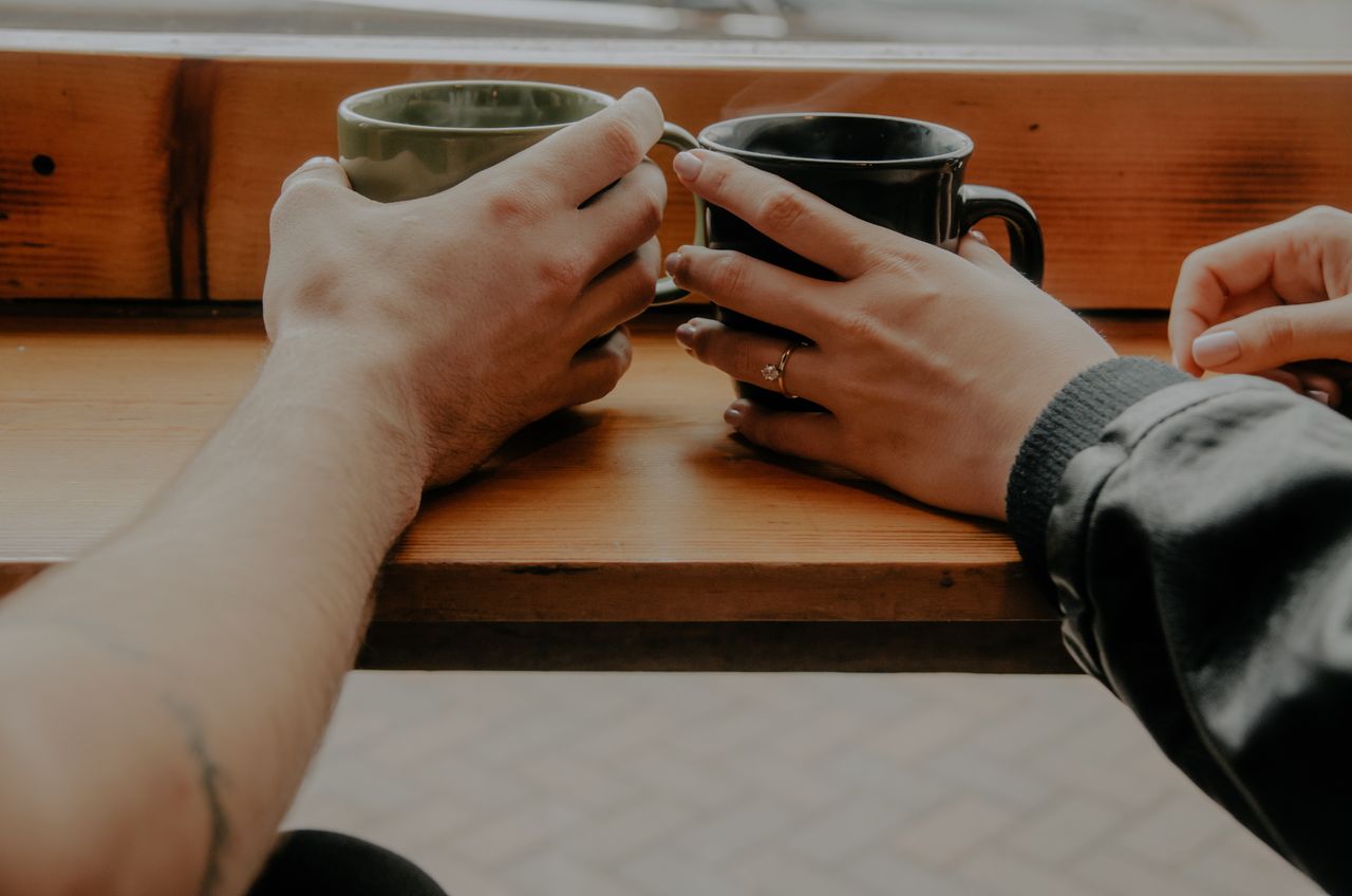 A woman and her partner drink coffee at a rustic cafe.