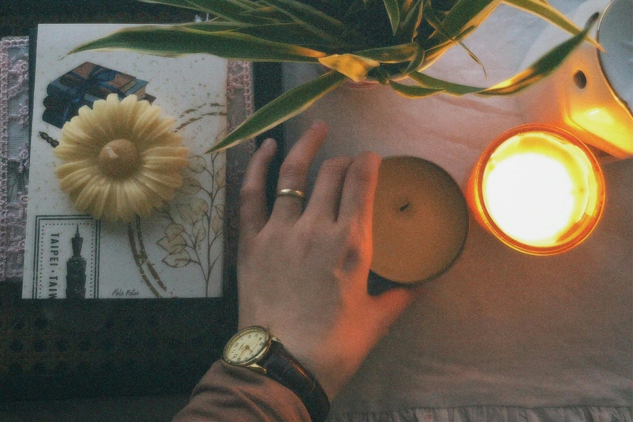A woman wearing a vintage watch placing a candle on a table.